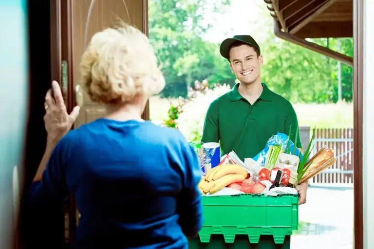 senior woman answering door to man delivering food