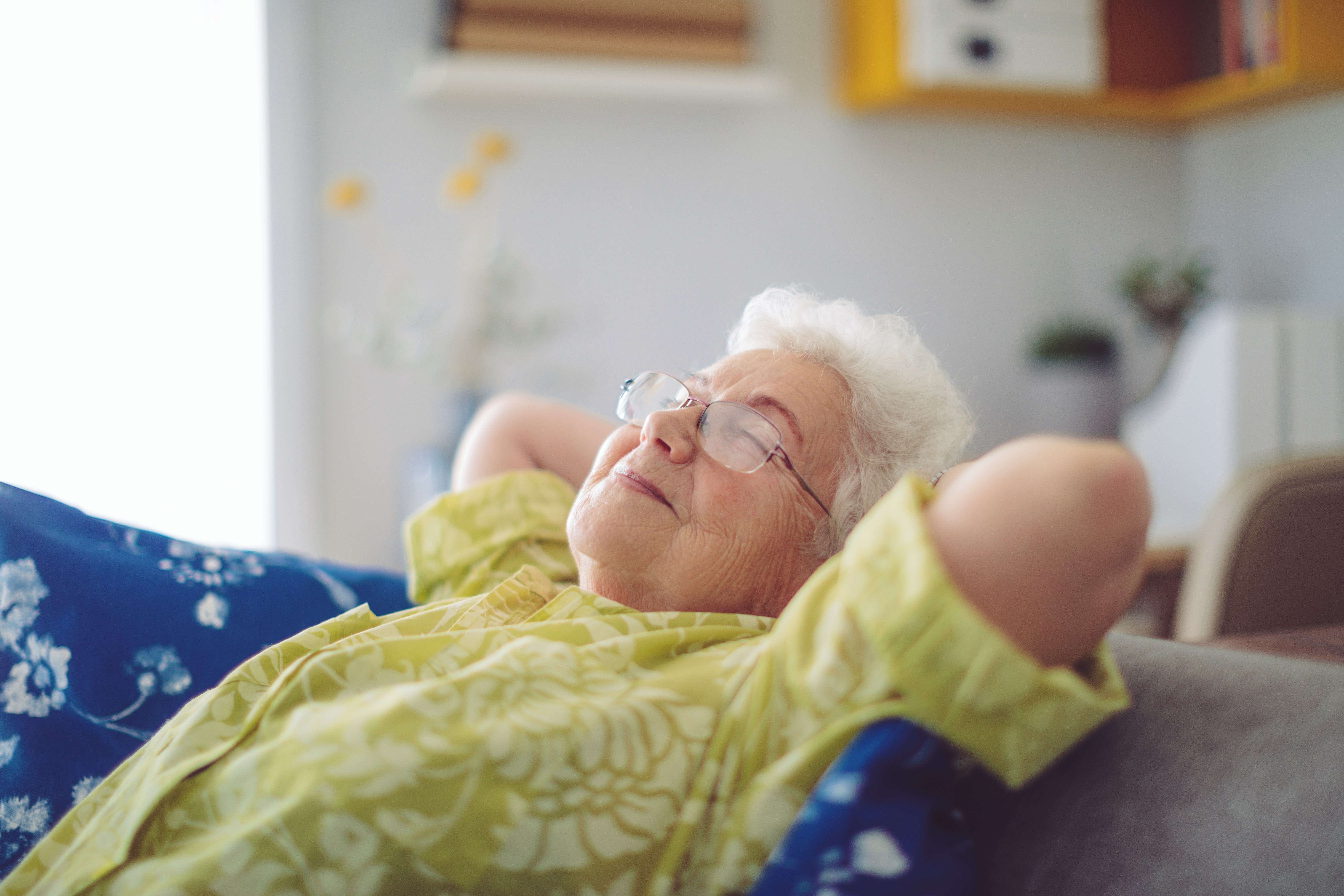 senior woman laying head back smiling while sitting on couch