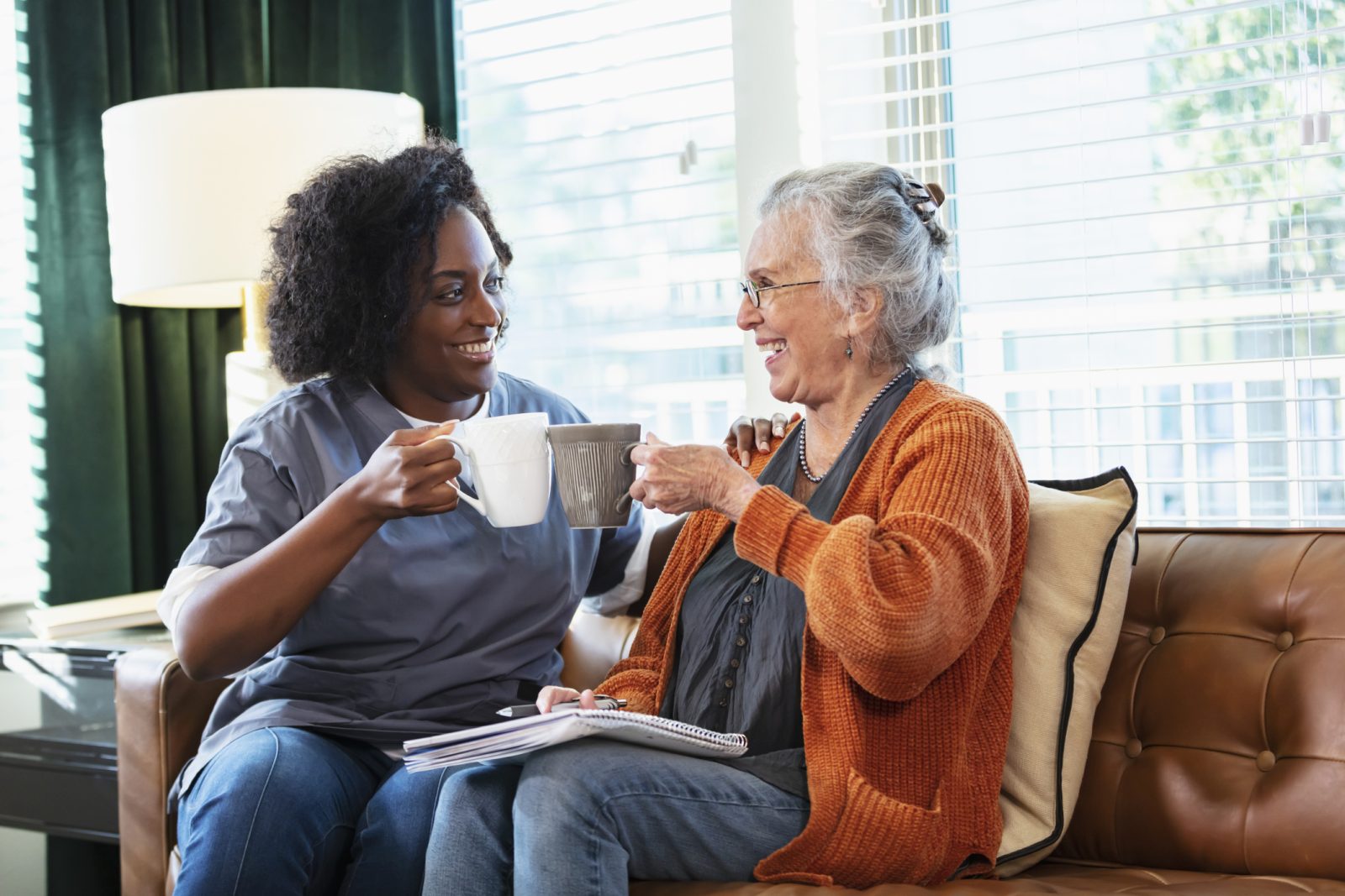 At-home companionship: caregiver and senior chatting on the couch for National Senior Citizens Day