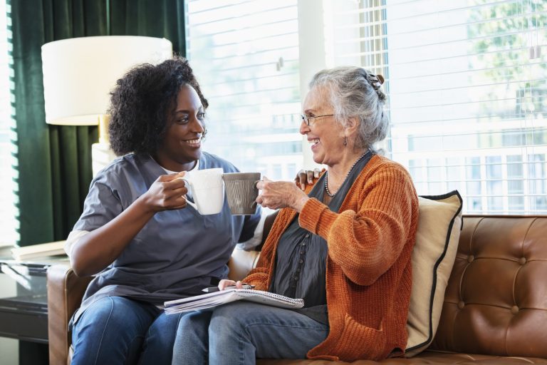 At-home companionship: caregiver and senior chatting on the couch for National Senior Citizens Day