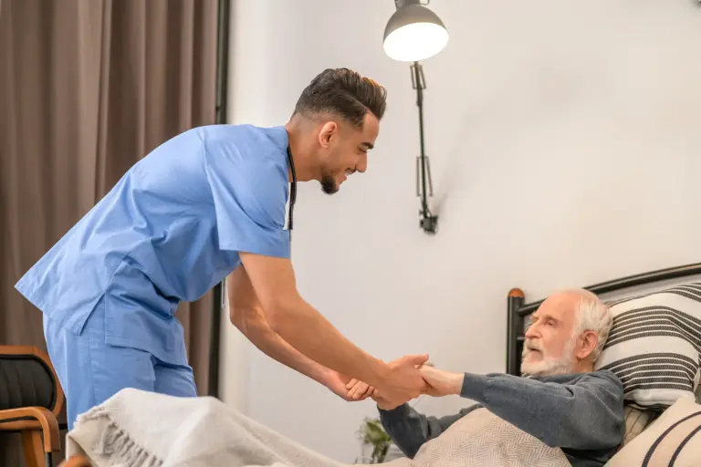 SYNERGY HomeCare helping an elderly man out of bed.