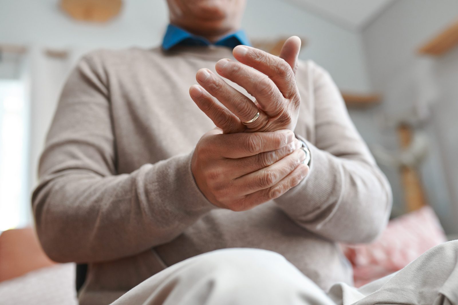 Close up image of man holding one of his wrists for comfort from inflammation