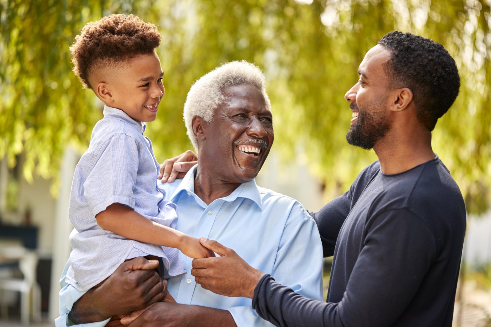 Smiling multi-generational family outdoors on Father's Day, highlighting the importance of male caregivers and in-home support for aging dads