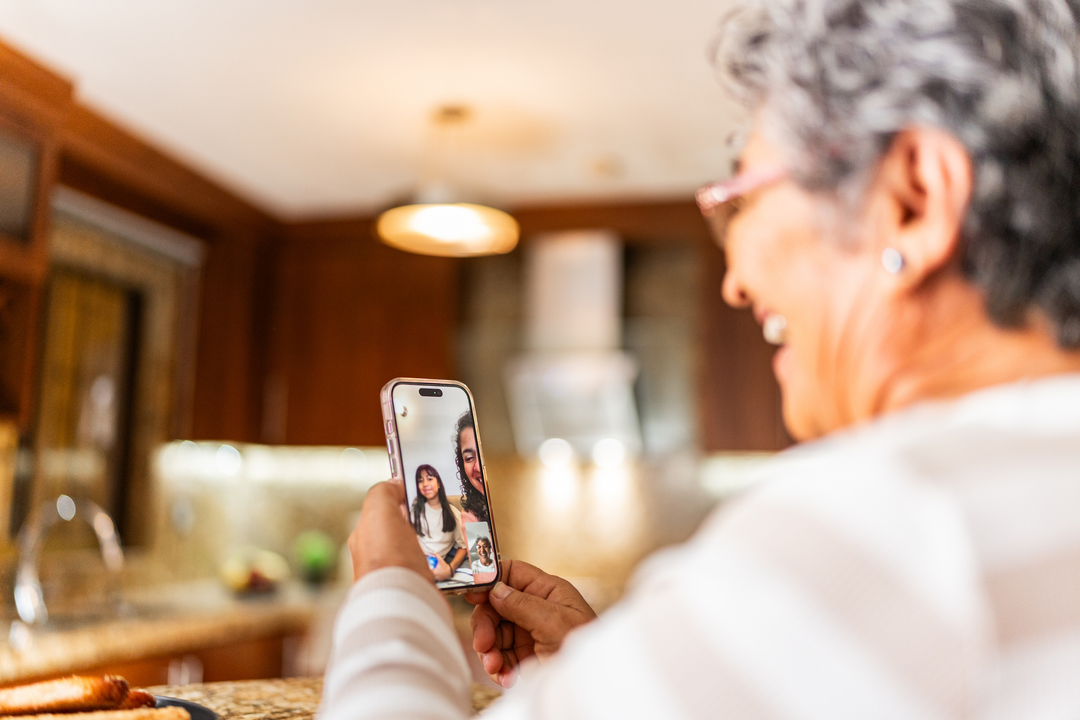 Senior woman video chatting with family from her living room, smiling and relaxed