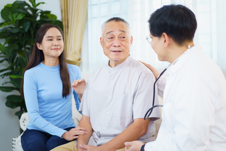 Senior man with family caregiver consulting a doctor during a healthcare visit