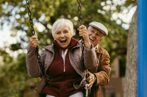 senior man pushing senior woman on a swing