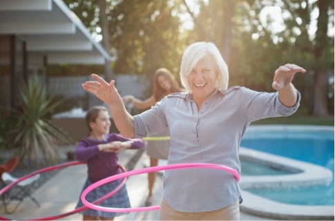 senior woman hula hooping with her grandkids