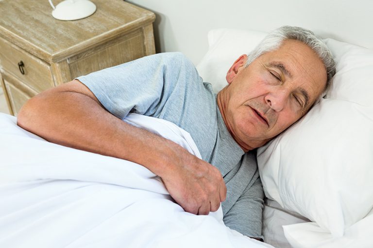 High angle view of senior man sleeping on bed at home