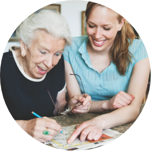 woman and senior woman enjoying doing a crossword puzzle together