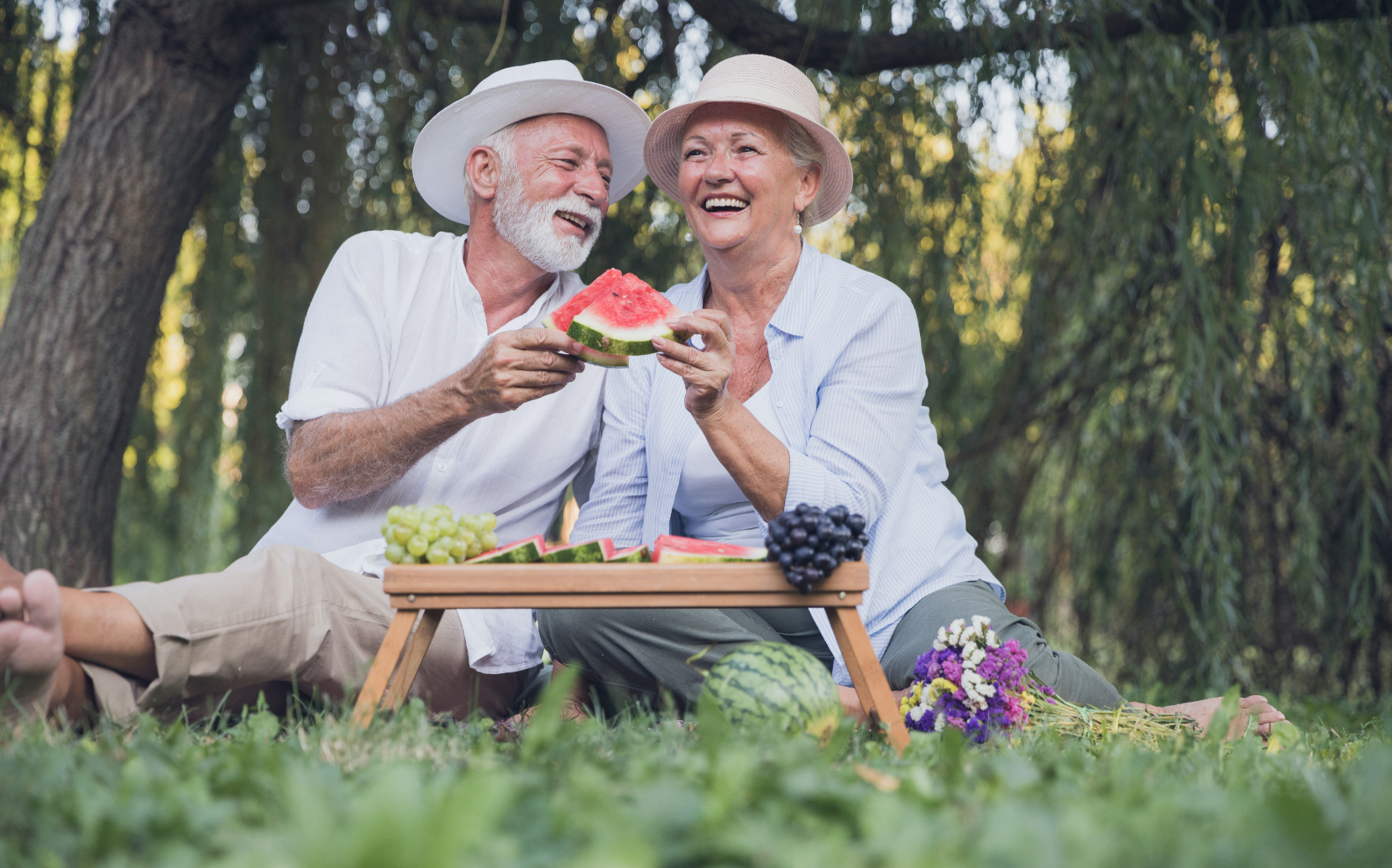 senior husband and wife enjoying eating watermelon outside during the summer