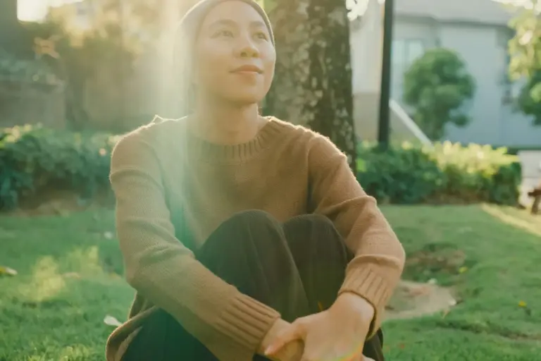 Cancer survivor sitting peacefully outdoors, symbolizing recovery and hope during National Cancer Survivor Month